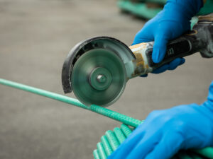 A handheld round saw is being used to cut a green tendon.