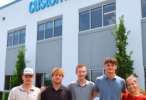 Interns posing in front of Custom Concrete building