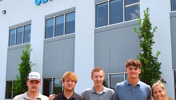 Interns posing in front of Custom Concrete building