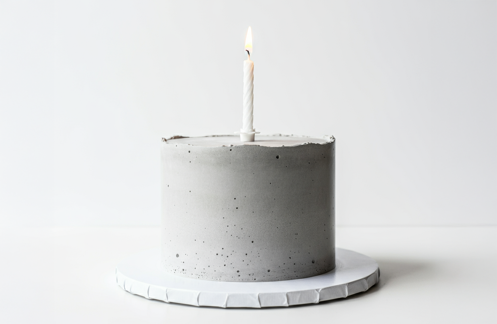 A concrete birthday cake with a single lit candle.