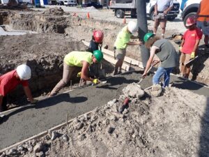 Youth apprentices pouring a footing for a concrete foundation.