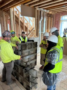 Six construction workers stand inside the wooden frame of a building.