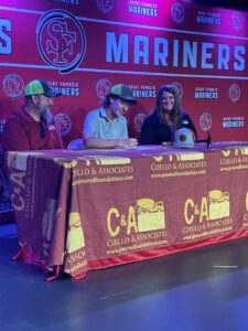 Three people sit at a table with a Coello and Associates branded tablecloth.
