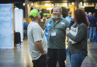 Three people stand and talk at CFACON25.