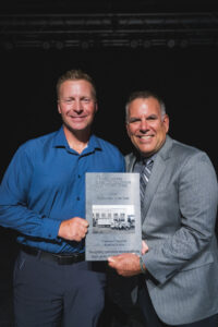 Two people pose with an award plaque.