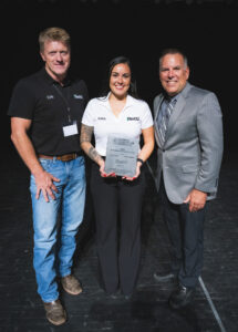Three people pose with an award plaque.