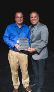Two men pose with an award plaque.