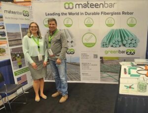 A man and a woman standing to the left in front of two presentation boards for mateenbar with a table to their right.
