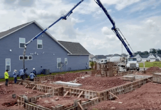 Wide shot of residential construction project with a tall crane and construction workers.