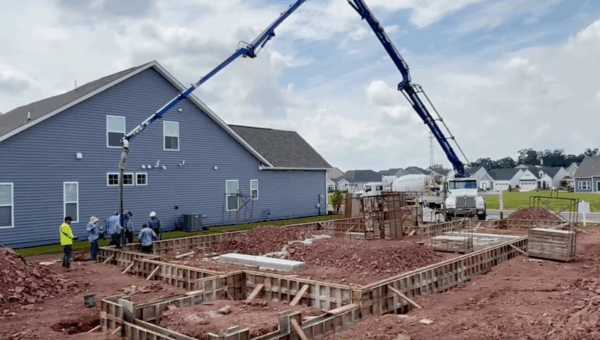 Wide shot of residential construction project with a tall crane and construction workers.