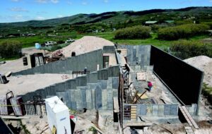 Side view of a concrete foundation with diagonal walls. A man stands inside one for scale of how large it is.