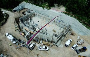 A one-room concrete foundation with wood supports and a tall concrete wall along the back. There is a red crane extended overtop.