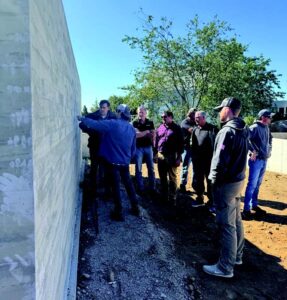 People stand looking at a concrete wall to the left while someone presents