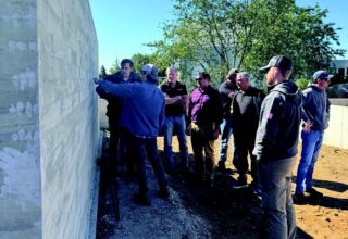 People stand looking at a concrete wall to the left while someone presents